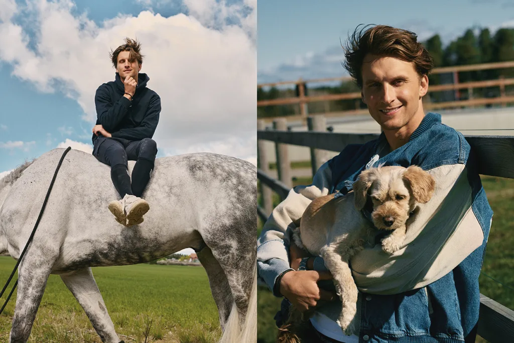 En ung man sitter på en grå häst på ett fält till vänster; till höger ler han medan han håller en liten hund i en denimslinga, stående vid ett trästaket med träd och himmel i bakgrunden.
