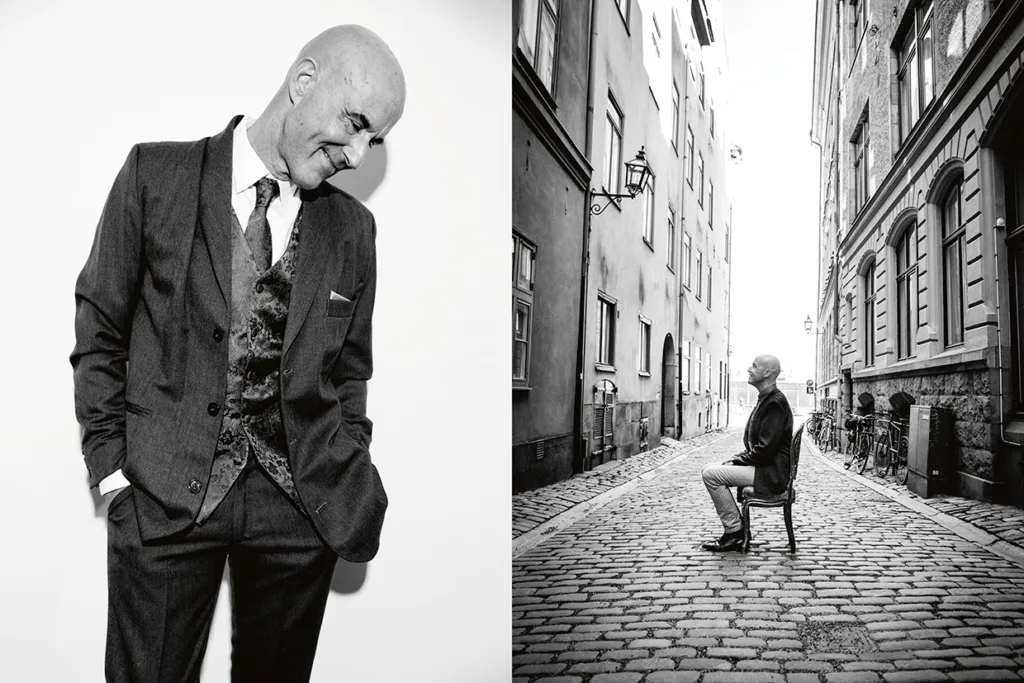 Vänster: Skallig Mark Levengod i kostym ler och tittar ner med händerna i fickorna, mot en enfärgad bakgrund. Till höger: Samma man sitter på en stol mitt på en kullerstensgata som kantas av gamla byggnader. Båda bilderna är svartvita.