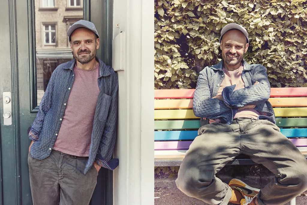 David Dencik i fritidskläder och keps poserar i två miljöer: han lutar sig mot en dörr utanför en byggnad och sitter med armarna i kors på en regnbågsfärgad bänk framför lövbuskar och ler på båda bilderna.