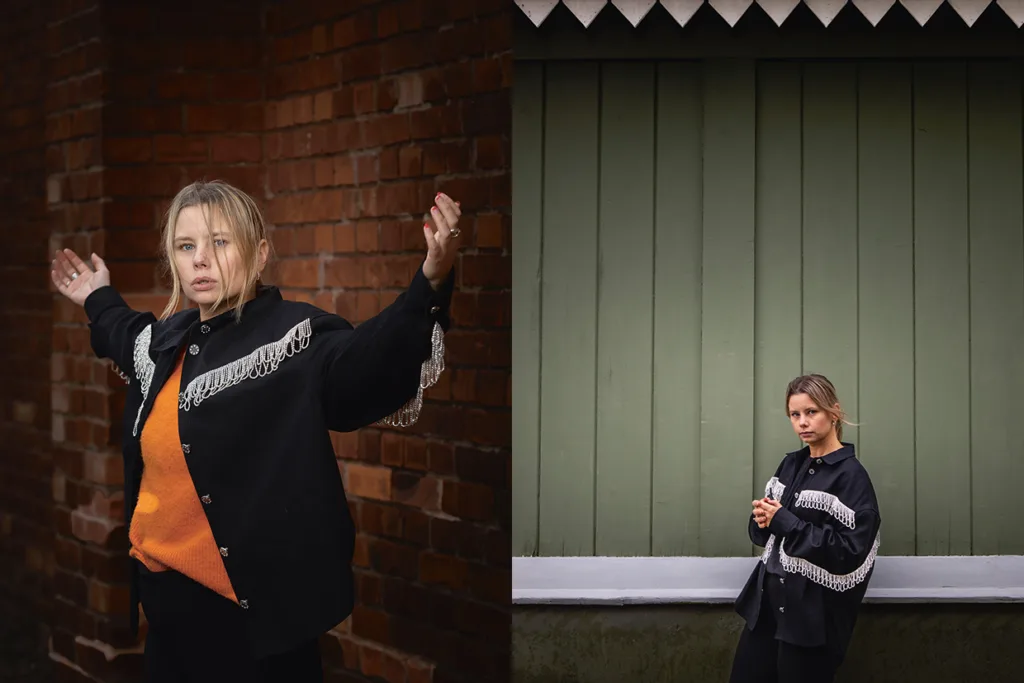 Amanda Jansson i svart jacka med silverfransar och orange topp poserar med armarna i vädret framför en tegelvägg (t.v.) och står med kragen i vädret framför en grön trävägg (t.h.).